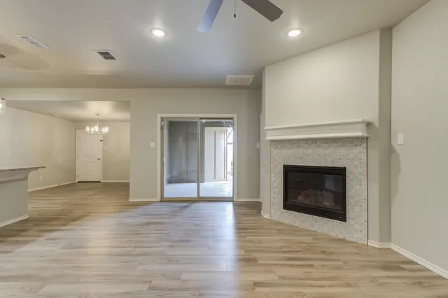 a view of an empty room with wooden floor fireplace and a window