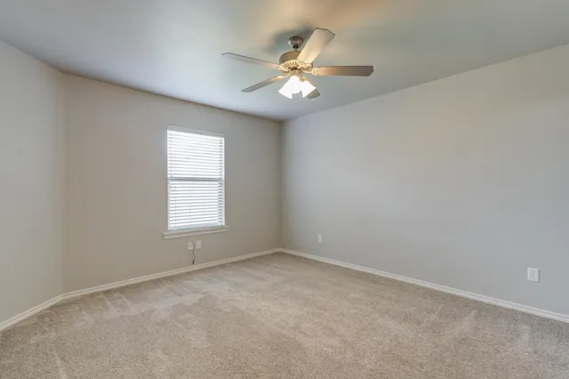 an empty room with windows and chandelier fan