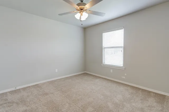 an empty room with a window and a fan