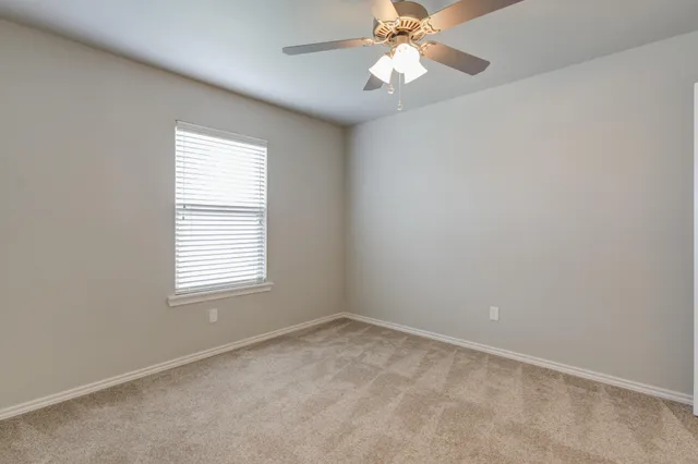 an empty room with a window and a fan