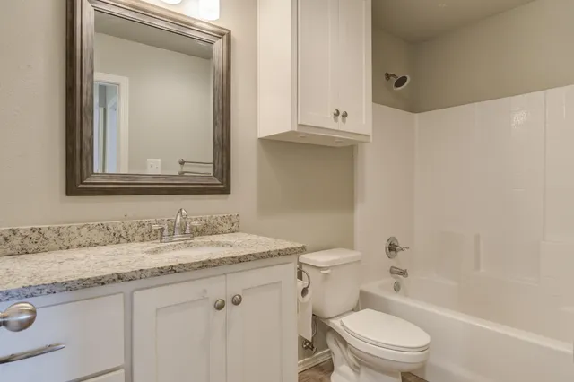 a bathroom with a granite countertop toilet a sink and a mirror