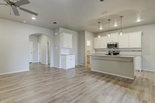 a kitchen with stainless steel appliances granite countertop a stove a sink and white cabinets with wooden floor