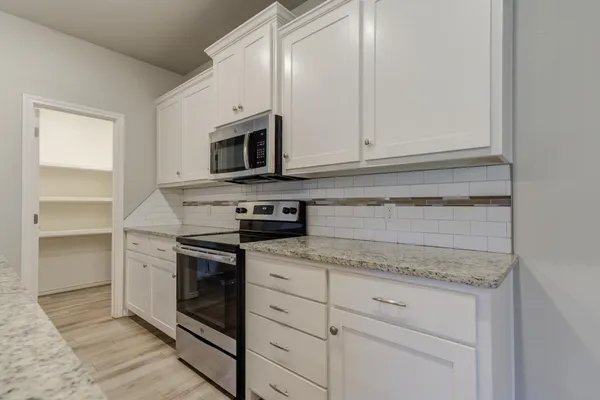a kitchen with granite countertop white cabinets and stainless steel appliances
