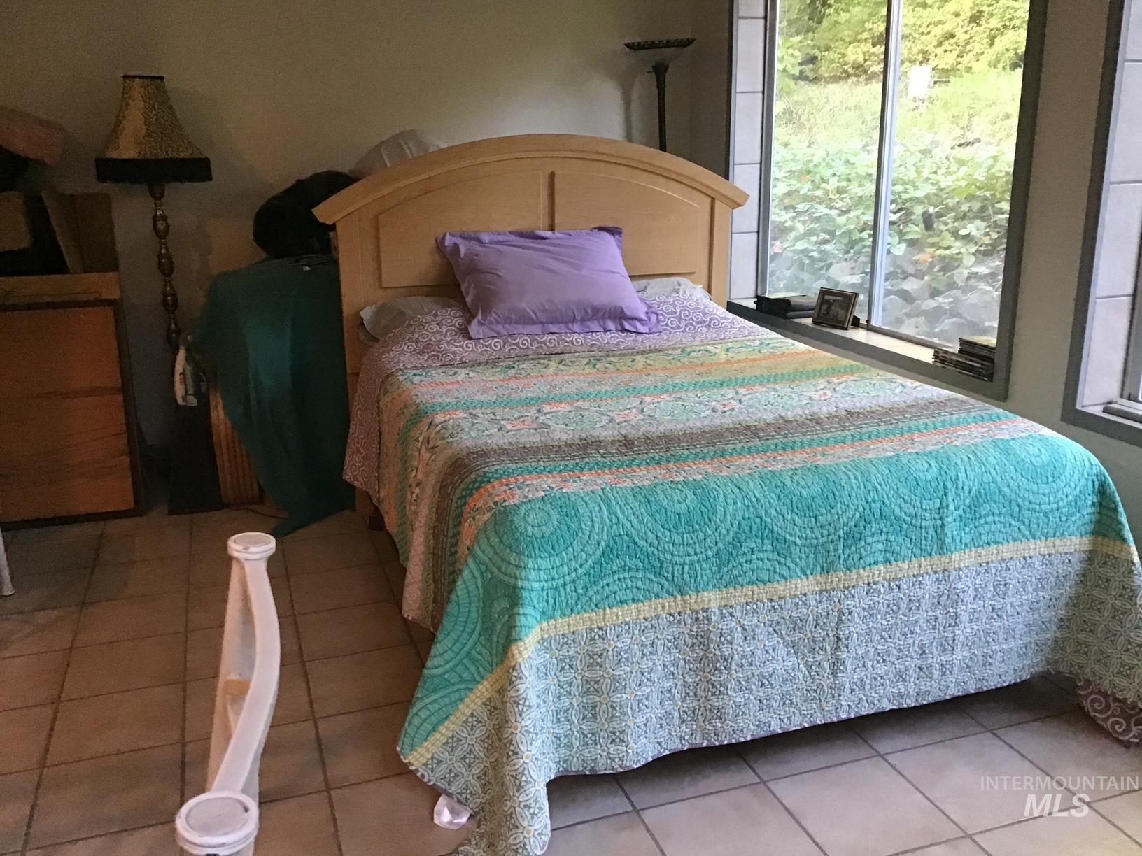 266 Falcon Ridge Road Kooskia, ID 83539 - Photo 28 of 50 Room featuring extensive window placement, light-toned tile flooring, and a light wood-finish headboard
