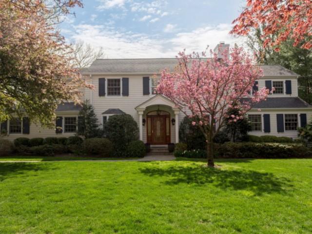 a front view of a house with garden and trees