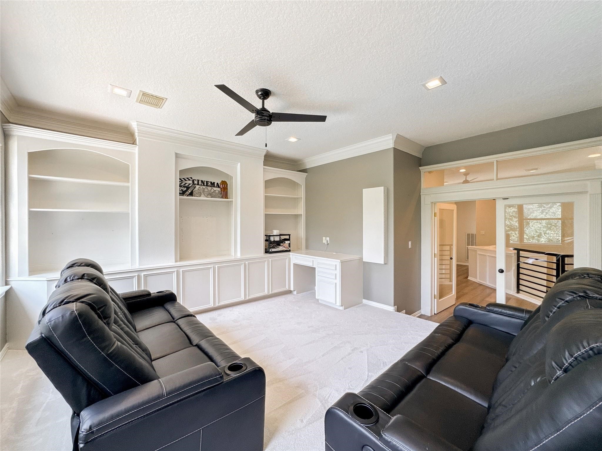 1810 Woerner Road Houston, TX 77090 - Photo 26 of 39 This spacious room features built-in shelves, a sleek ceiling fan, and comfortable leather seating, ideal for a home theater setup. The neutral color palette and ample lighting create a cozy, inviting atmosphere.