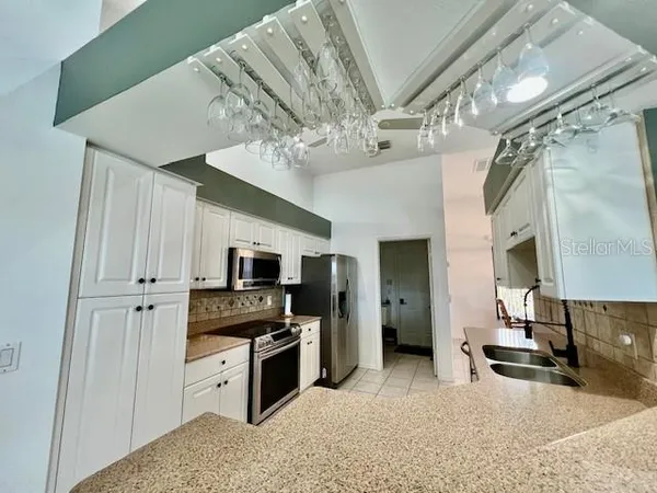 a kitchen with granite countertop a refrigerator and a stove top oven