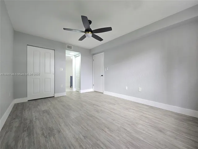 a view of empty room with wooden floor and ceiling fan