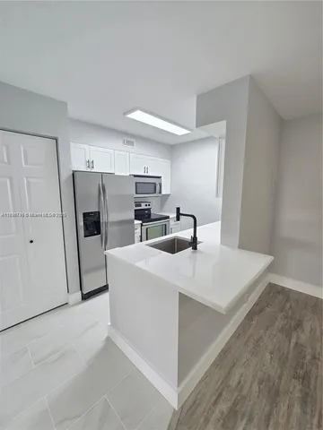 a kitchen with refrigerator and white cabinets