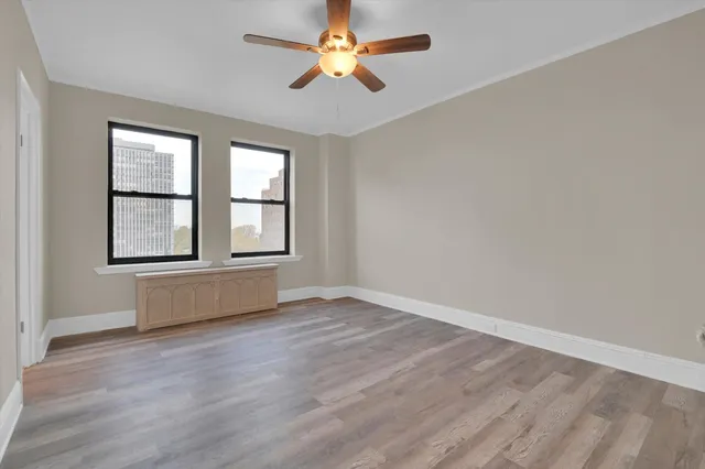 an empty room with chandelier fan and windows