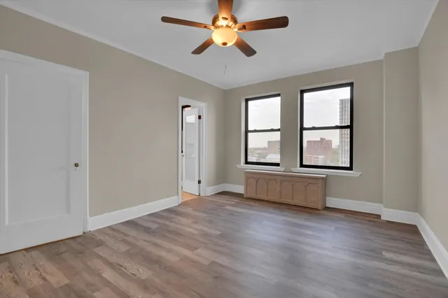 an empty room with wooden floor and a ceiling fan