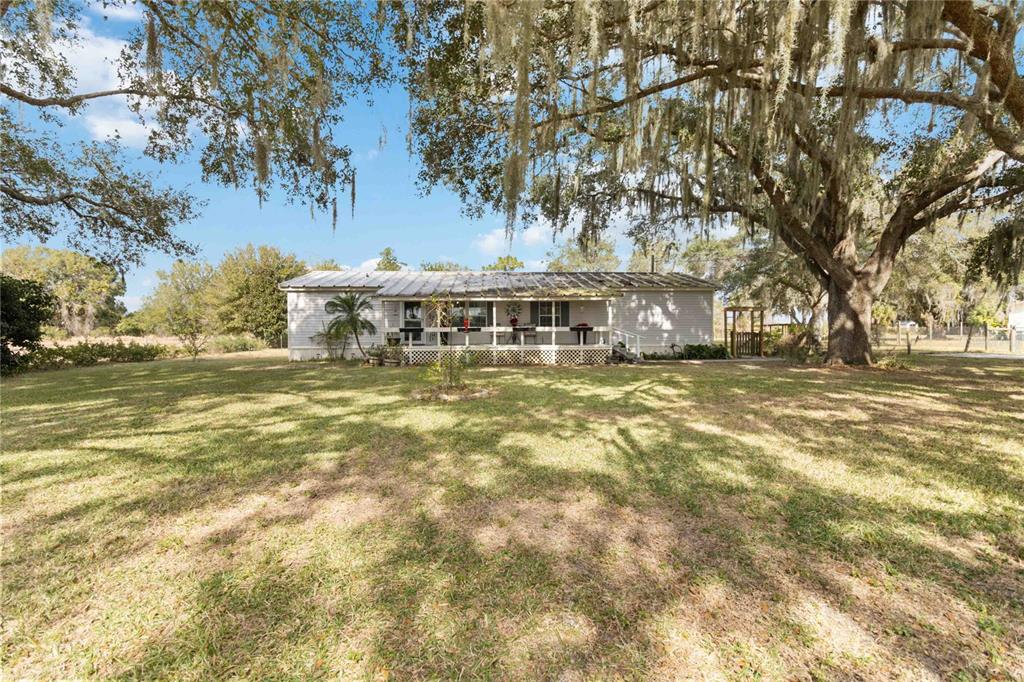 a view of a house with a big yard and large trees
