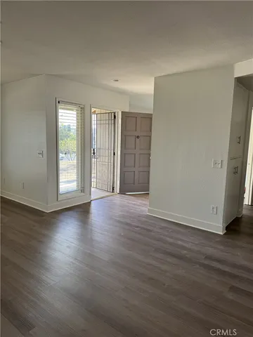 a view of an empty room with wooden floor and window