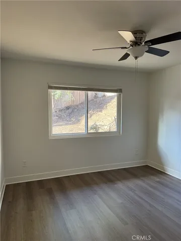 an empty room with wooden floor fan and windows