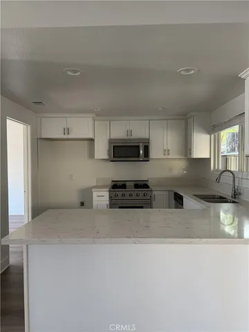 a kitchen with stainless steel appliances granite countertop a stove a sink a refrigerator and white cabinets