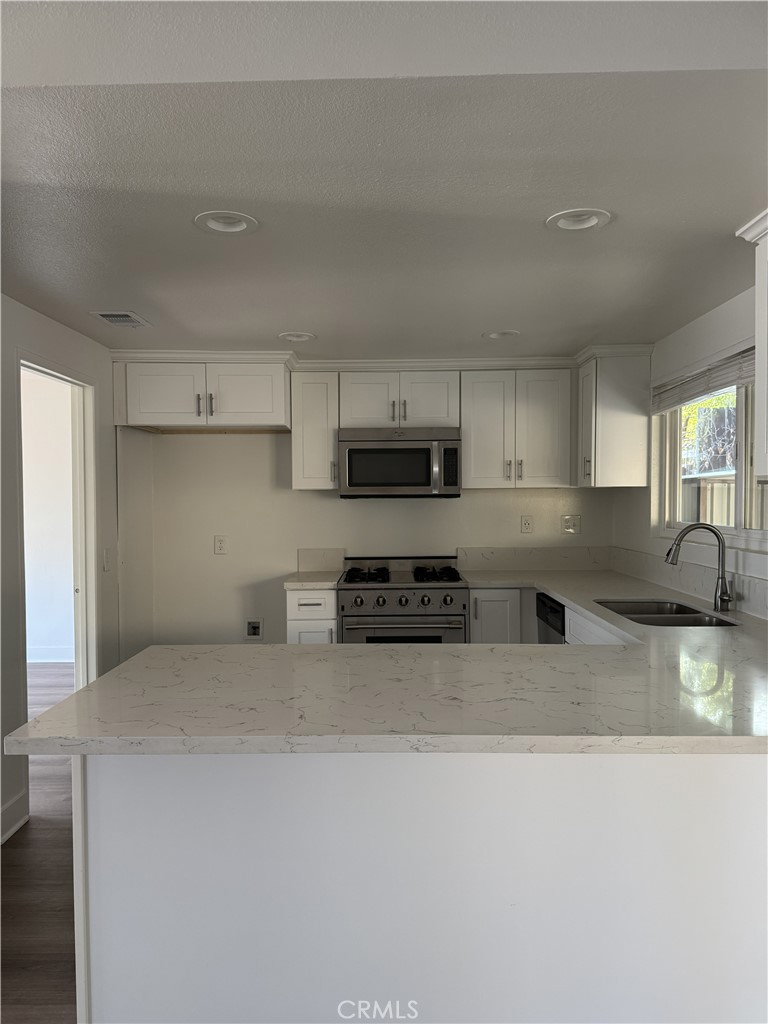 15521 Saddleback Road Woodcrest, CA 92506 - Photo 9 of 24 a kitchen with stainless steel appliances granite countertop a stove a sink a refrigerator and white cabinets