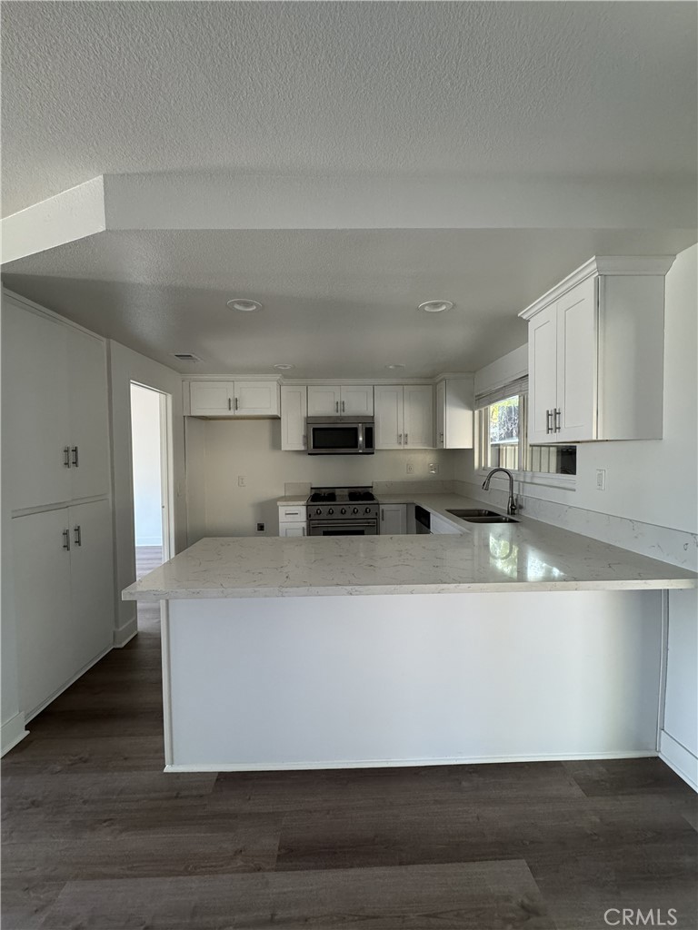 15521 Saddleback Road Woodcrest, CA 92506 - Photo 10 of 24 a large white kitchen with kitchen island granite countertop a stove top oven a sink and white cabinets