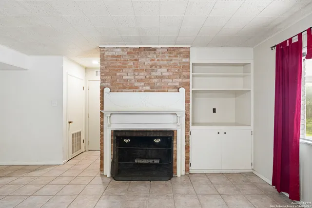 an empty room with windows and fireplace