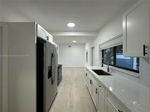 a kitchen with granite countertop a sink and refrigerator