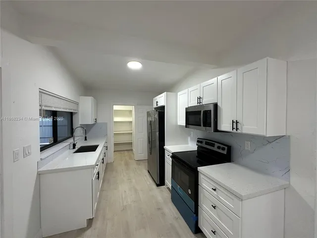 a kitchen with granite countertop a sink stove and refrigerator