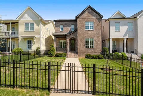 a view of a brick house with a big yard and plants