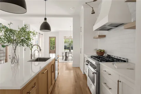 a kitchen with stainless steel appliances a stove a chimney a sink and a chandelier