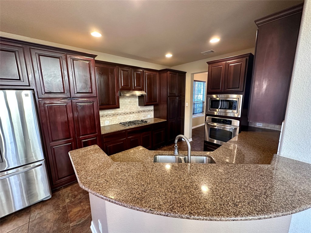 3713 Broadwinged Hawk Cove Austin, TX 78738 - Photo 11 of 37 a kitchen with stainless steel appliances granite countertop a refrigerator and a sink