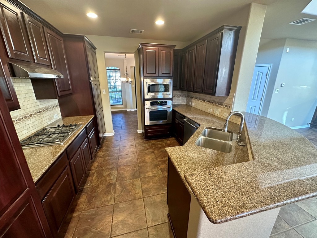 3713 Broadwinged Hawk Cove Austin, TX 78738 - Photo 12 of 37 a kitchen with kitchen island granite countertop a stove and a sink