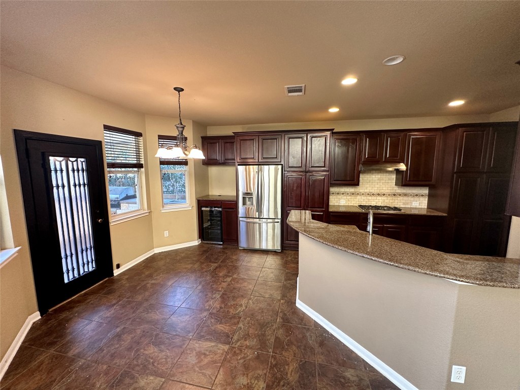 3713 Broadwinged Hawk Cove Austin, TX 78738 - Photo 10 of 37 a kitchen with stainless steel appliances kitchen island granite countertop a refrigerator oven a sink and dishwasher