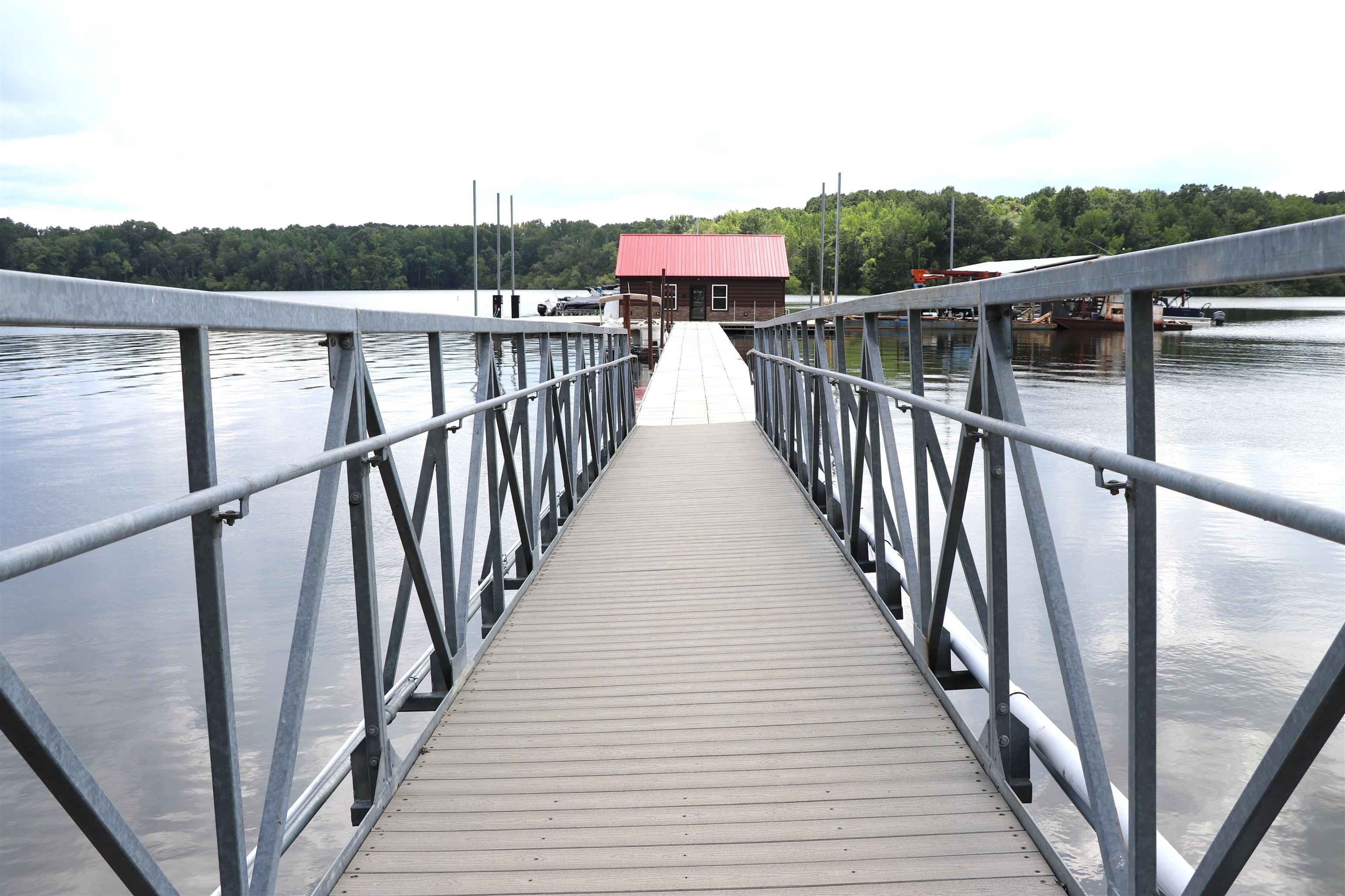 160 Patrick Drive Springville, TN 38256 - Photo 29 of 34 Floating dock system featuring composite decking, galvanized steel railings, and a red-roofed boathouse