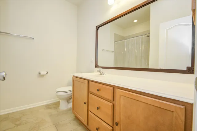 a bathroom with a granite countertop toilet sink and mirror