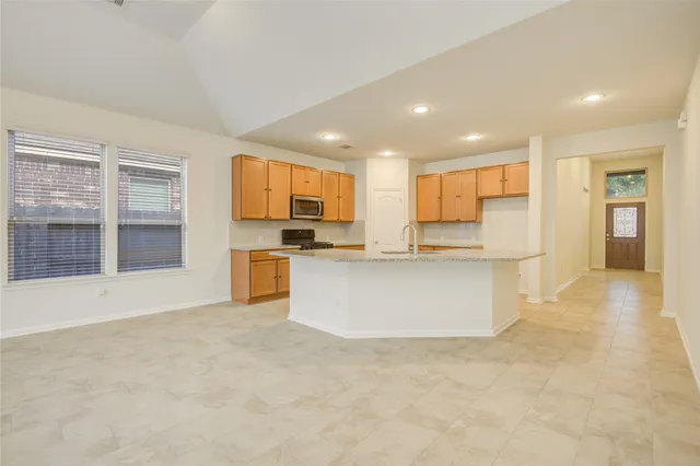 a view of kitchen with kitchen island wooden cabinets and refrigerator