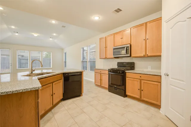 a large kitchen with granite countertop a stove top oven a sink a granite counter space and cabinets