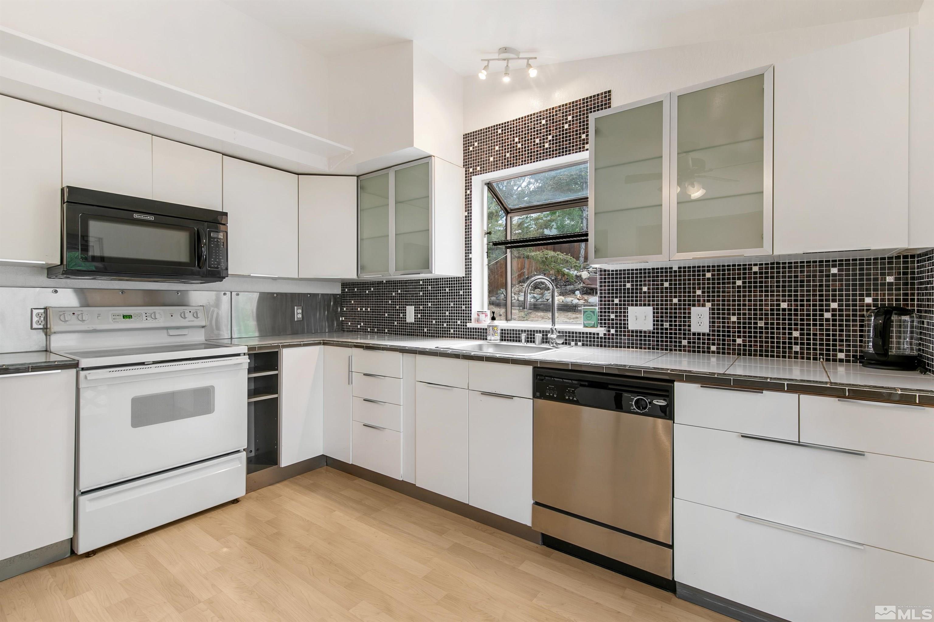 1394 Ambassador Drive Reno, NV 89523 - Photo 9 of 28 a kitchen with granite countertop white cabinets and white appliances
