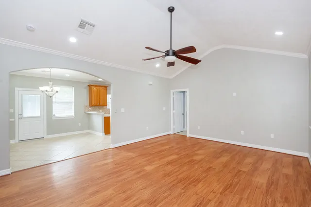 a view of an empty room with a window and wooden floor