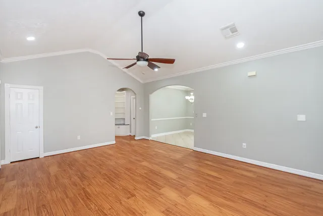 a view of a room with a chandelier fan and wooden floor