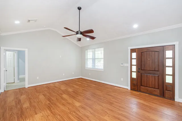 a view of an empty room with window and wooden floor