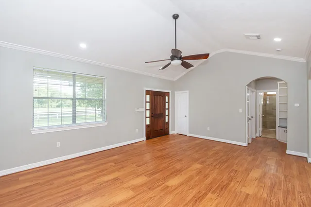 a view of an empty room with window and wooden floor