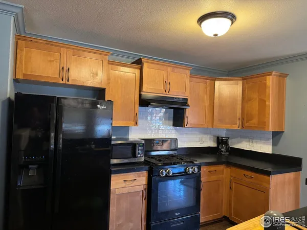 a kitchen with stainless steel appliances granite countertop a refrigerator a sink dishwasher a stove and a dining table with wooden floor