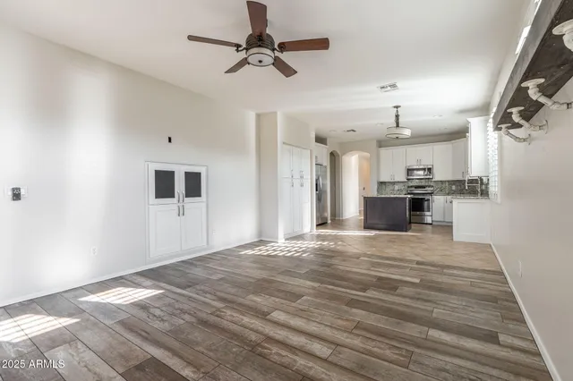 a view of empty room with wooden floor and kitchen view
