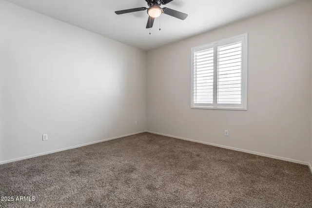 an empty room with a window and a ceiling fan