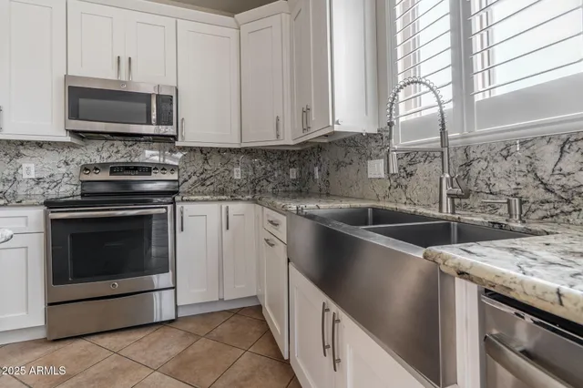 a kitchen with granite countertop a sink stove and microwave