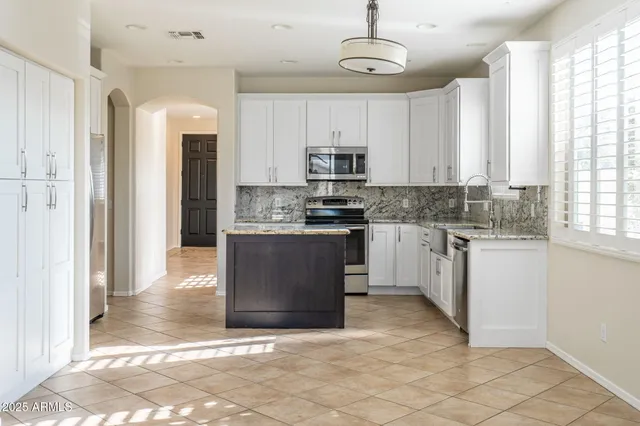 a kitchen with stainless steel appliances granite countertop a stove top oven a refrigerator a sink and a window