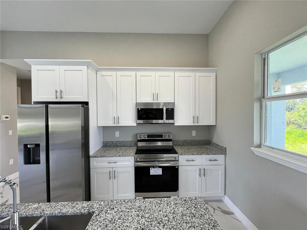 3115 58th Street West Lehigh Acres, FL 33971 - Photo 2 of 14 a kitchen with a refrigerator stove and microwave