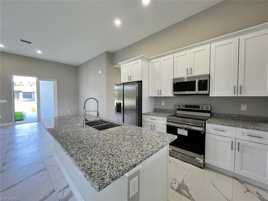 3115 58th Street West Lehigh Acres, FL 33971 - Photo 3 of 14 a kitchen with stainless steel appliances granite countertop a sink stove and cabinets