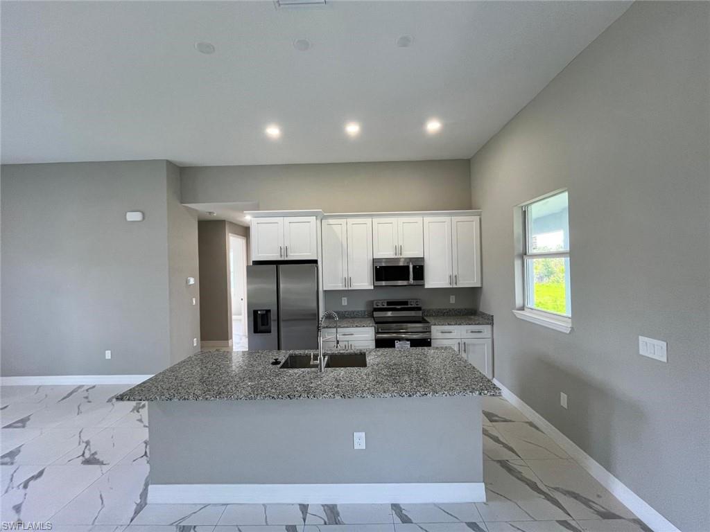3115 58th Street West Lehigh Acres, FL 33971 - Photo 4 of 14 a kitchen with stainless steel appliances granite countertop a sink a stove and a refrigerator