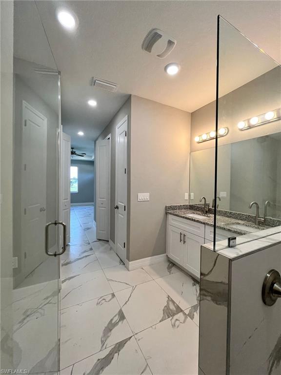 3115 58th Street West Lehigh Acres, FL 33971 - Photo 6 of 14 a bathroom with a double vanity sink a large mirror and shower