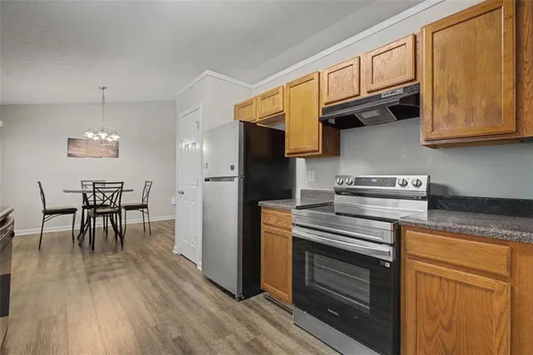 a kitchen with stainless steel appliances granite countertop a stove a refrigerator and a dining table with wooden floor