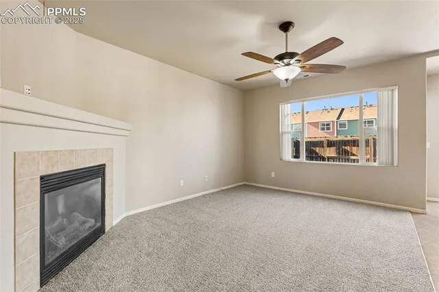 a view of an empty room with window and chandelier fan