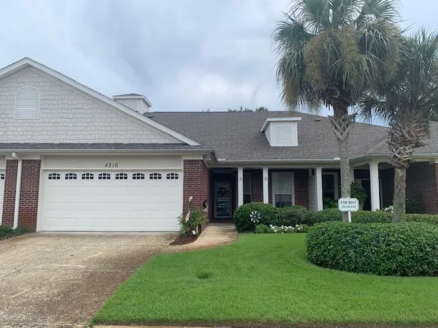 a front view of a house with a garden and palm trees